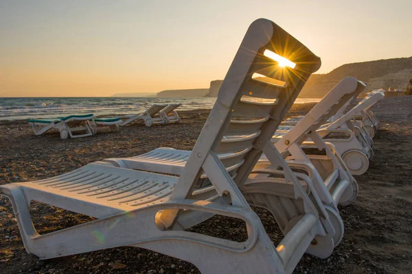 Camas de sol brancas em uma praia de areia ao pôr do sol — Fotografia de Stock