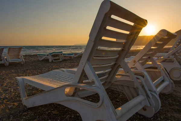 Weiße Sonnenliegen an einem Sandstrand bei Sonnenuntergang — Stockfoto