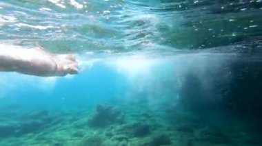 Su altında, arkadaşlarının berrak deniz suyunda birlikte şnorkelle yüzmelerini izlemek.
