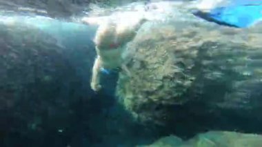 Bikinili bir kızın kristal berrak deniz suyunda şnorkelle dalışının sualtı görüntüsü.