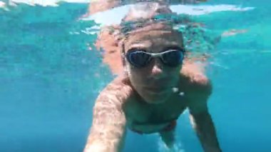 Yüzen bir adamın deniz suyunda eğlendiği sualtı görüntüsü