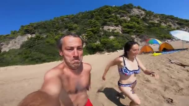 Ζευγάρι Τρέχει Στην Παραλία Και Πηδά Στο Νερό Της Θάλασσας — Αρχείο Βίντεο