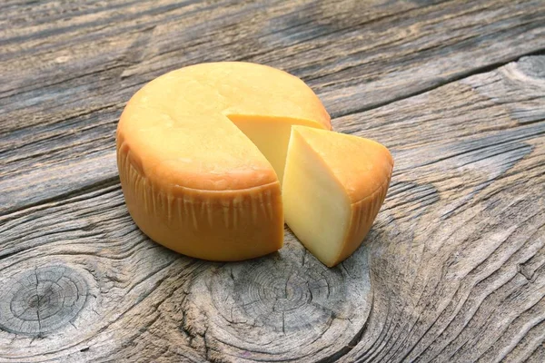 Rueda de queso sobre mesa de madera —  Fotos de Stock