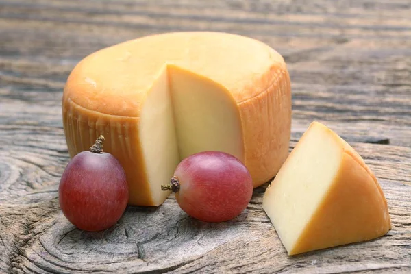 Rueda de queso sobre mesa de madera —  Fotos de Stock