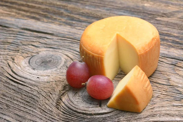 Rueda de queso sobre mesa de madera —  Fotos de Stock