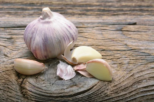 Aglio biologico intero e spicchi sullo sfondo di legno — Foto Stock