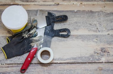 Tadilat ve inşaat kavramı, toolings ahşap zemin arka plan, çalışma eldiven, spatula, macun, bıçak ve kılavuz çatlaklar için onarım