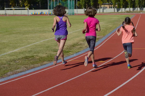 Fitness familiar, madre activa y niños corriendo en pista de estadio, vista trasera, entrenamiento con concepto de deporte infantil — Foto de Stock