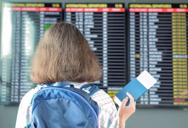 Kvinde turist i lufthavnsterminal venter på flyvning og ser på tidsplanen med pas og billet, rejser koncept - Stock-foto