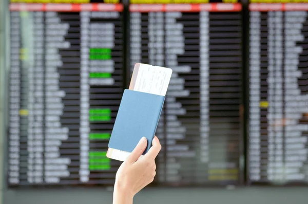 Lufthavn og rejsekoncept, hånd med pas og flybilletter med tidsplan baggrund i terminal - Stock-foto