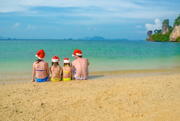 Rodinná dovolená na vánoční a novoroční svátky, šťastný rodičů a dětí v santa klobouky mají zábavu na pláži, cestování s dětmi — Stock fotografie