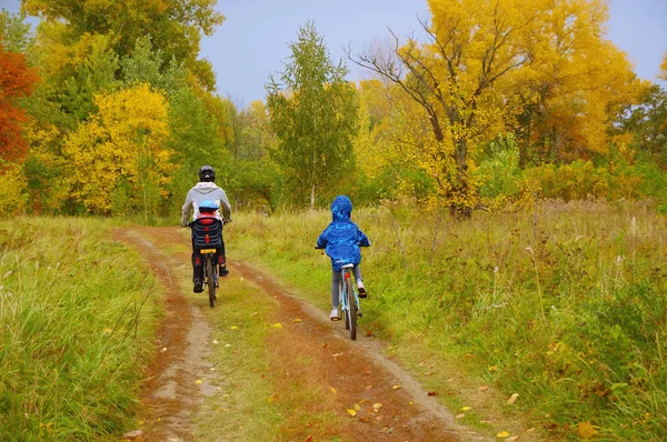Family on bikes in golden autumn park, father and kids cycling on trail, active sport with children outdoors — Stock Photo, Image