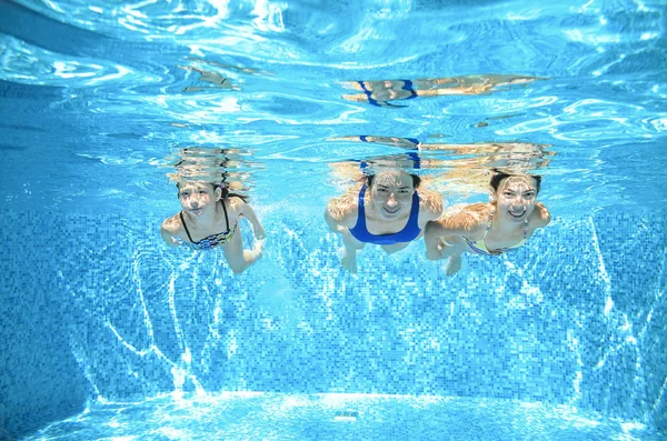 Family swims in pool under water, happy active mother and children have fun, fitness and sport with kids on summer vacation — Stock Photo, Image