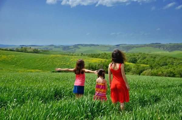 Happy family having fun outdoors on green field, mother and children on spring vacation in Tuscany, travel with kids in Italy — Stock Photo, Image