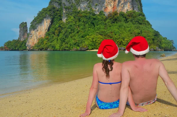 Christmas and New Year holidays on tropical beach, romantic couple in santa hats sitting near sea, Thailand, Krabi — Stock Photo, Image