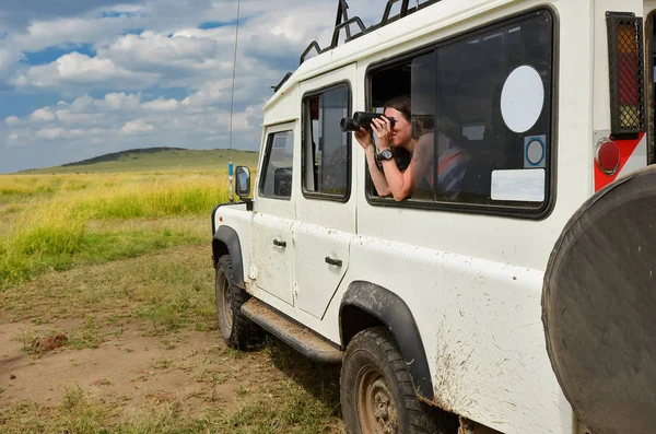 在非洲旅行的女游客，在肯尼亚旅行，用双筒望远镜观察稀树草原的野生动物 — 图库照片