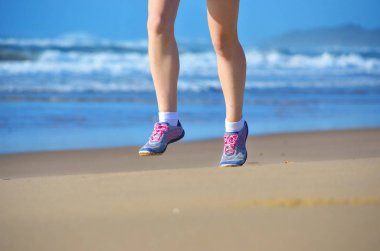 Fitness ve kumsalda, kadın runner bacaklar ayakkabı kum deniz, sağlıklı yaşam ve spor kavramı üzerinde çalışan