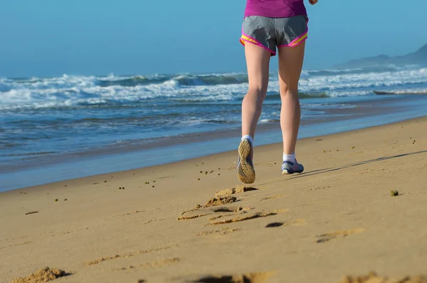 Fitness en draait op strand, benen van de loper van de vrouw in de schoenen op zand in de buurt van de zee, gezonde levensstijl en sport concept — Stockfoto