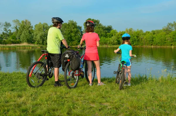 Família em bicicletas ao ar livre, pais ativos e criança pedalar e relaxar perto de belo rio, conceito de fitness — Fotografia de Stock