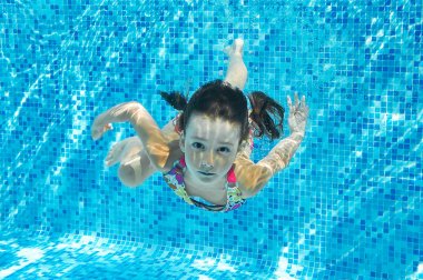 Çocuk havuzunda sualtı, etkin kız dalışlar ve eğlenir su, çocuk fitness ve spor altında ailecek tatile mutlu yüzüyor