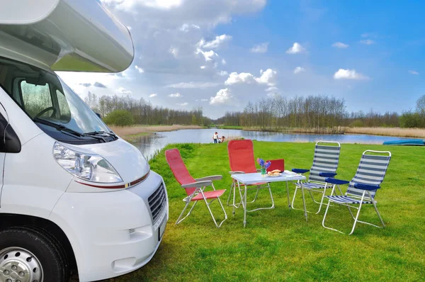 Family vacation, RV (camper) travel concept, motorhome, table and chairs in holiday campsite, kids on background — Stock Photo, Image