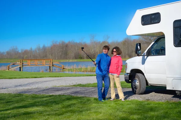 Vacaciones familiares, viajes en autocaravana, pareja feliz haciendo selfie en frente de campista en viaje de vacaciones en autocaravana — Foto de Stock