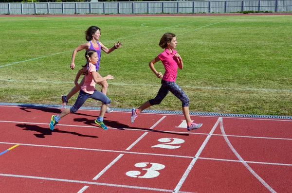 Rodinné fitness, matka a děti běh na stadionu trať, trénink a děti sport zdravý životní styl koncept — Stock fotografie