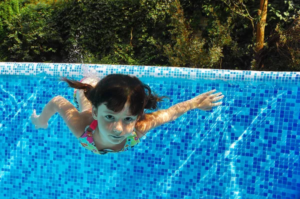 Criança nada na piscina subaquática, menina ativa feliz mergulha e se diverte na água, criança fitness e esporte em férias em família — Fotografia de Stock