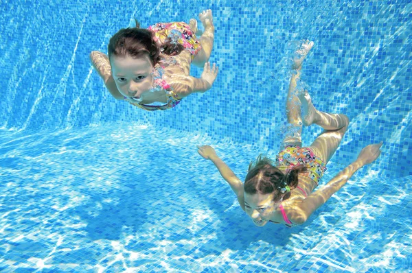 Children swim in pool underwater, happy active girls have fun in water, kids fitness and sport on active family vacation — Stock Photo, Image