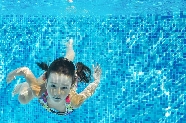 Niño nada en la piscina bajo el agua, inmersiones de chica activa feliz y se divierte, fitness para niños y deporte en vacaciones en familia — Foto de Stock