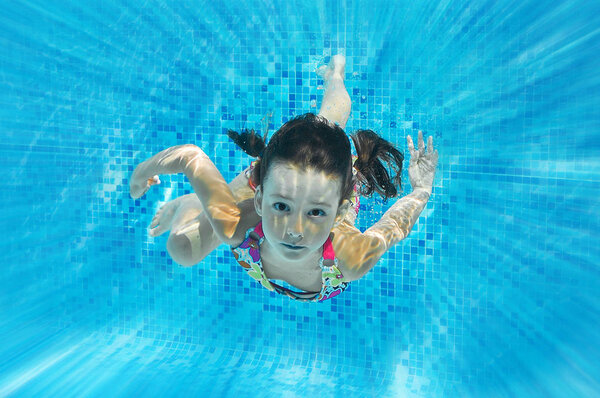Ребенок плавает в бассейне под водой, счастливая активная девушка ныряет и весело проводит время под водой, детский фитнес и спорт на семейном отдыхе
