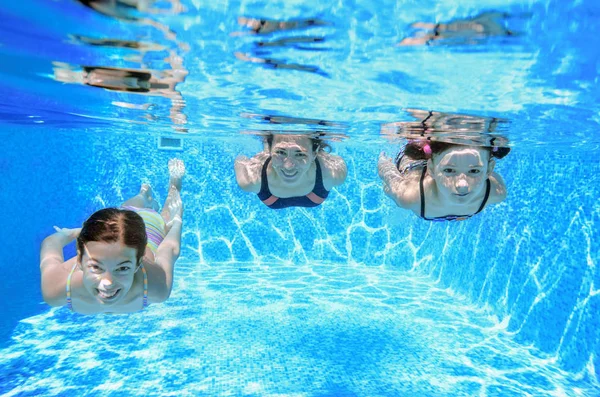 Family swimming in pool under water, happy active mother and children have fun, fitness and sport with kids on summer vacation — Stock Photo, Image