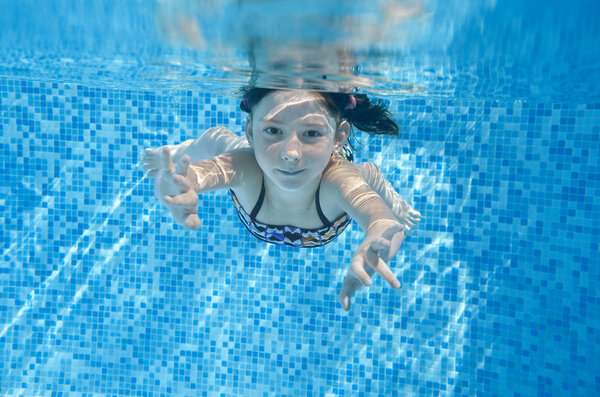 Ребенок плавает в бассейне под водой, счастливая активная девушка ныряет и весело проводит время под водой, детский фитнес и спорт на семейном отдыхе
