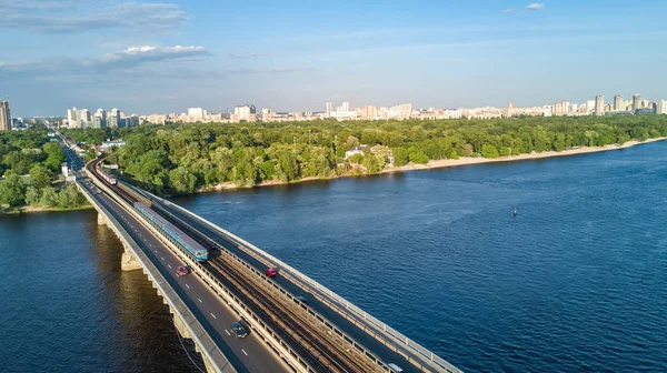 Luchtfoto bovenaanzicht van Metro spoorwegbrug met trein en Dnjepr above, skyline van de stad van Kiev, Oekraïne — Stockfoto