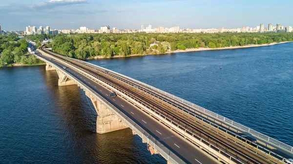 Luchtfoto bovenaanzicht van Metro spoorwegbrug met trein en Dnjepr above, skyline van de stad van Kiev, Oekraïne — Stockfoto