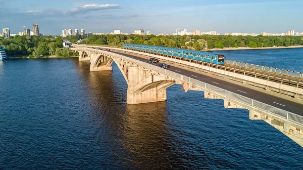 Αεροφωτογραφία πάνω από σιδηροδρομική γέφυρα του μετρό με τρένο και στον ποταμό Δνείπερο από ψηλά, στον ορίζοντα της πόλης του Κιέβου, Ουκρανία — Φωτογραφία Αρχείου