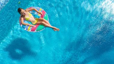 Havadan görünümü bir kız yukarıda, yüzme havuzunda Yüzme şişme halka çörek üzerinde çocuk ve eğlenir suda ailecek tatile