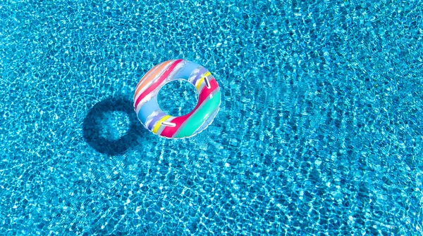 Vista aerea del giocattolo gonfiabile colorato della ciambella dell'anello nell'acqua della piscina dall'alto, sfondo di concetto di vacanza della famiglia — Foto Stock