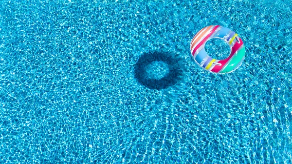 Vista aérea do brinquedo inflável colorido do donut do anel na água da piscina de cima, fundo do conceito das férias da família — Fotografia de Stock