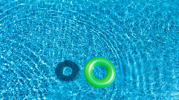 Aerial view of colorful inflatable ring donut toy in swimming pool water from above, family vacation concept background — Stock Photo, Image