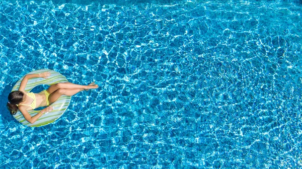 Aerial view of girl in swimming pool from above, kid swim on inflatable ring donut and has fun in water on family vacation — Stock Photo, Image