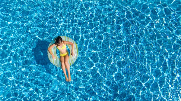 Luftaufnahme von Mädchen im Schwimmbad von oben, Kind schwimmt auf aufblasbarem Ring Donut und hat Spaß im Wasser im Familienurlaub — Stockfoto