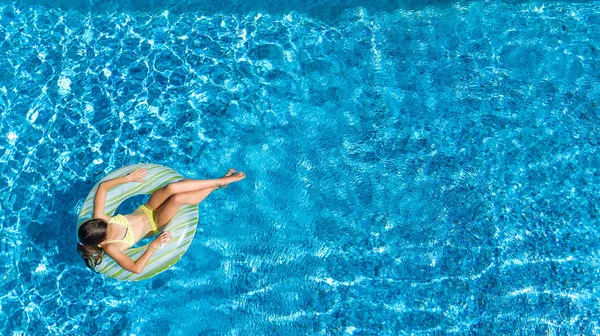 Vue aérienne de la fille dans la piscine d'en haut, l'enfant nage sur beignet anneau gonflable et s'amuse dans l'eau pendant les vacances en famille — Photo
