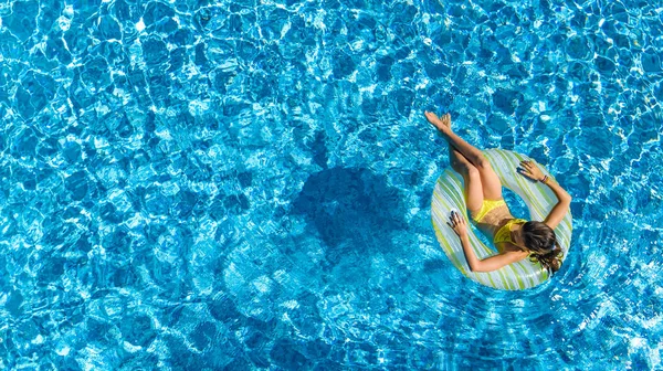 Vue aérienne de la fille dans la piscine d'en haut, l'enfant nage sur beignet anneau gonflable et s'amuse dans l'eau pendant les vacances en famille — Photo