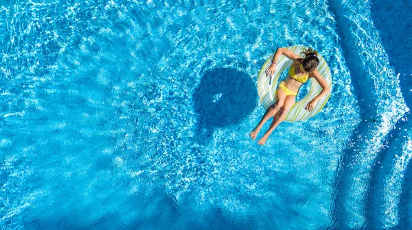 Vue aérienne de la fille dans la piscine d'en haut, l'enfant nage sur beignet anneau gonflable et s'amuse dans l'eau pendant les vacances en famille — Photo