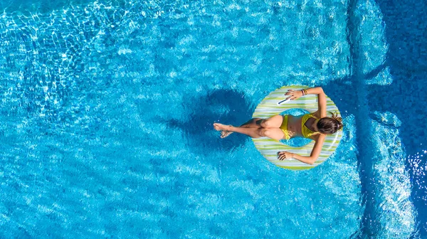 Vista aérea de la niña en la piscina desde arriba, el niño nada en el anillo inflable donut y se divierte en el agua en vacaciones familiares — Foto de Stock