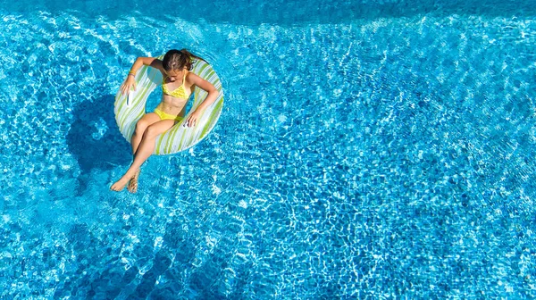 Vue aérienne de la fille dans la piscine d'en haut, l'enfant nage sur beignet anneau gonflable et s'amuse dans l'eau pendant les vacances en famille — Photo