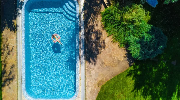 Vista aérea de la niña en la piscina desde arriba, el niño nada en el anillo inflable donut y se divierte en el agua en vacaciones familiares —  Fotos de Stock