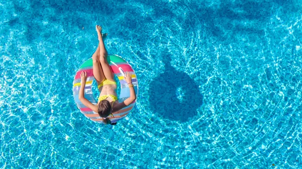 Vue aérienne de la fille dans la piscine d'en haut, l'enfant nage sur beignet anneau gonflable et s'amuse dans l'eau pendant les vacances en famille — Photo