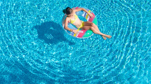 Vista aérea de la niña en la piscina desde arriba, el niño nada en el anillo inflable donut y se divierte en el agua en vacaciones familiares —  Fotos de Stock